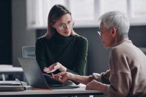 A couple reviews life insurance papers and a calculator at a kitchen table.